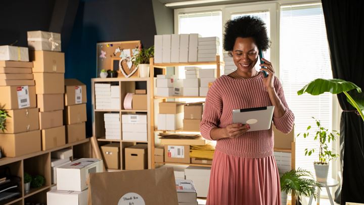 Female owner of business startup standing in her office with a bunch of boxes